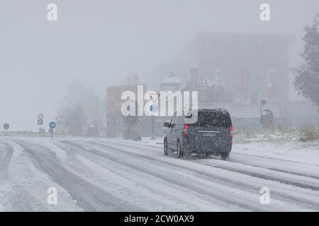 Feldberg, Deutschland. September 2020. Nach dem ersten Schneefall fährt ein Auto auf einer verschneiten Straße am Feldberg im Schwarzwald. Quelle: Andreas Rosar/Fotoagentur-Stuttgart/dpa - ACHTUNG: Kennzeichen wurde aus rechtlichen Gründen verpixelt/dpa/Alamy Live News Stockfoto