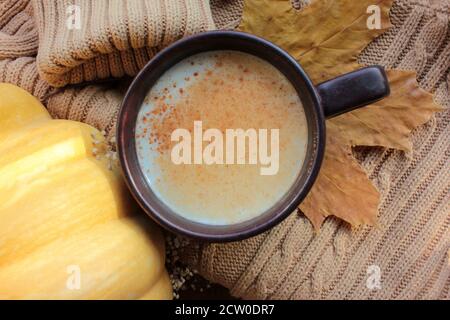 Tasse Kürbis Latte mit Zimt, Pullover, Kürbis und Herbstblättern. Gemütliches Herbstkonzept. Herbst flach Lay Zusammensetzung. Selektiver Fokus Stockfoto