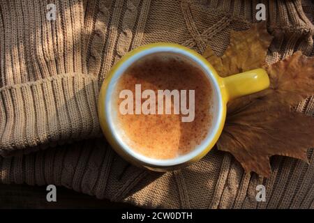 Tasse Kürbis Latte mit Zimt, Pullover, Kürbis und Herbstblättern. Gemütliches Herbstkonzept. Herbst flach Lay Zusammensetzung. Selektiver Fokus Stockfoto