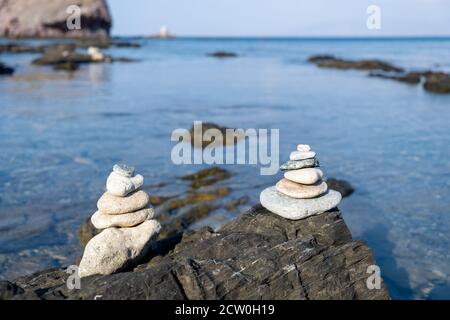 Pyramide aus balancierenden weißen Kieselsteinen, auf dem Felsen eines felsigen Strandes Stockfoto