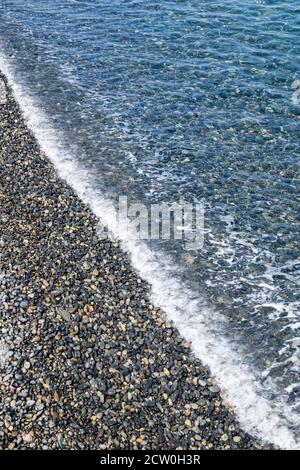 Meereswellen plätschern zu einem Kiesstrand felsigen Strand gegen bewölkt Himmel Stockfoto