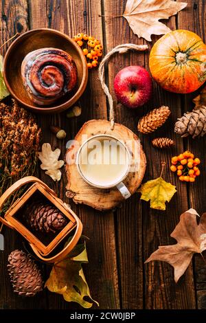 Köstlicher Cappuccino mit einem Brötchen auf herbstlichem Hintergrund. Komfort zu Hause Stockfoto