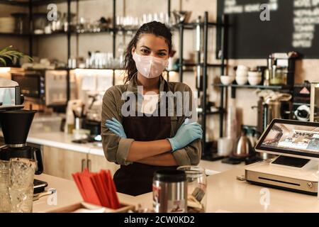 Frau mit Gesichtsmaske steht an der Theke, Shop nach dem Lockdown geöffnet Stockfoto