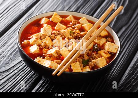 Mapo Tofu ist ein berühmtes Sichuan Gericht, bestehend aus Tofu, gehacktes Schweinefleisch, heiße Sauce in der Nähe auf dem Teller auf dem Tisch. Horizontal Stockfoto