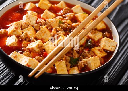 Zarte Mapo Tofu in einer aromatischen und würzigen Sauce gekocht, begleitet von Hackfleisch Nahaufnahme in der Platte auf dem Tisch. Horizontal Stockfoto