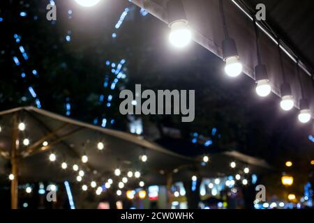 Textile Regenschirm mit Holzrahmen und String Lichter glühen mit weißem Licht auf Hinterhof Terrasse, Stadtbild Nacht Szene mit Girlande, niemand. Stockfoto