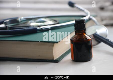 Jodtinktur in einem kleinen Glasbecher, ein Buch und medizinische Geräte. Gesundheitskonzept Stockfoto