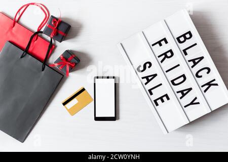 Leuchtkasten mit schwarzem Freitagstext, leeres Smartphone für Online-Shopping-Design und präsentiert Draufsicht auf weißem Hintergrund. Online-Shopping in Black Frid Stockfoto
