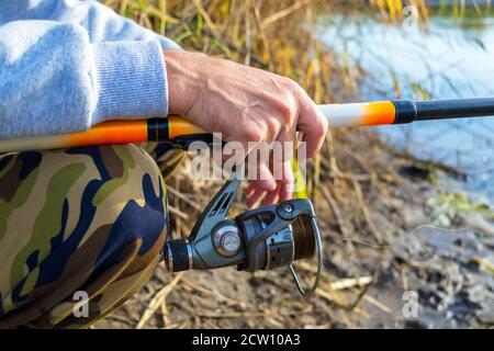 Hände des Fischers halten Angelrute mit Haspel Stockfoto