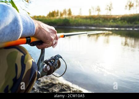 Hände des Fischers halten Angelrute mit Haspel Stockfoto