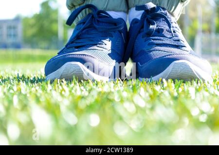 Männliche Füße in Sport-Sneakers stehen auf grünem Gras Stockfoto