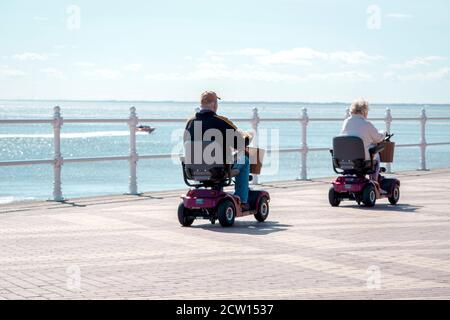 Älterer Mann und Frau auf Mobilitätsrootern auf der Promenade In Bridlington East Yorkshire Stockfoto