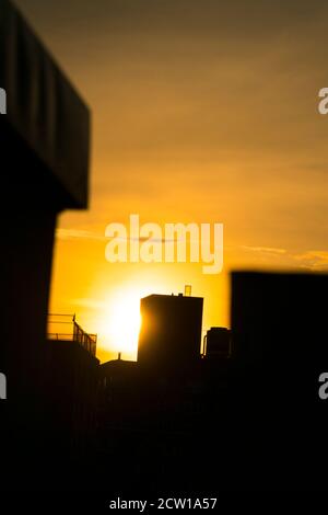 Die Sonne untergeht unter den East Village Gebäuden in New York City. Stockfoto