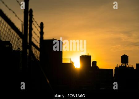 Die Sonne untergeht unter den East Village Gebäuden in New York City. Stockfoto