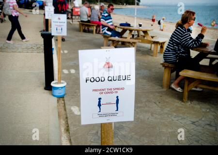 Isle of Wight, September 2020. Bembridge. Schild für die Essenswarteschlange mit Covid-Warnung Stockfoto