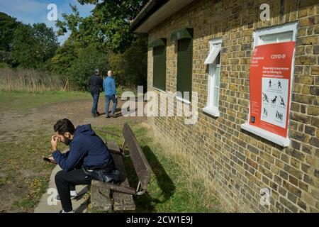 Besucher des Hampstead Heath Parks mit Schildern, die darauf hinweisen, dass sie es behalten sollten Sichere soziale Distanz durch Coronavirus / Covid-19 Pandemie in London, England, Großbritannien Stockfoto