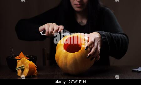 Junge Brünette Frau schnitzt einen Kürbis für Halloween Vorbereitung Stockfoto