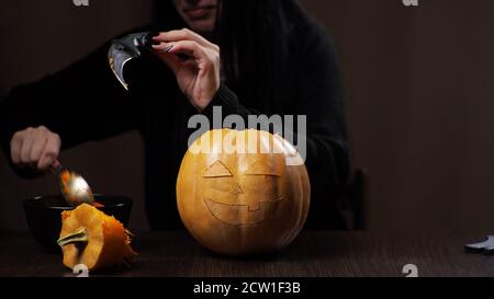 Junge Brünette Frau schnitzt einen Kürbis für Halloween Vorbereitung Stockfoto