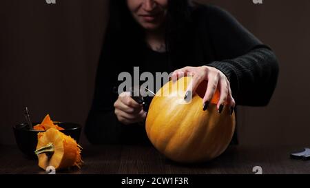 Junge Brünette Frau schnitzt einen Kürbis für Halloween Vorbereitung Stockfoto