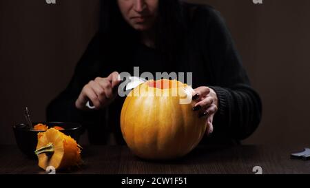Junge Brünette Frau schnitzt einen Kürbis für Halloween Vorbereitung Stockfoto
