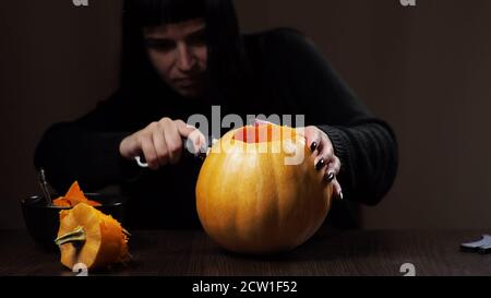 Junge Brünette Frau schnitzt einen Kürbis für Halloween Vorbereitung Stockfoto