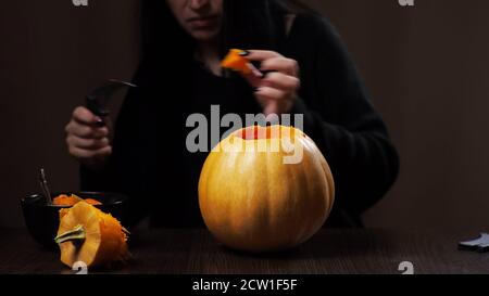 Junge Brünette Frau schnitzt einen Kürbis für Halloween Vorbereitung Stockfoto