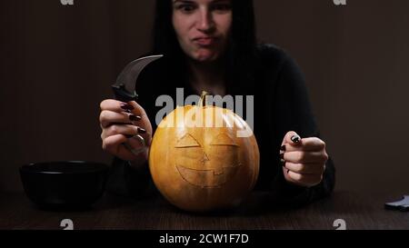Junge Brünette Frau schnitzt einen Kürbis für Halloween Vorbereitung Stockfoto