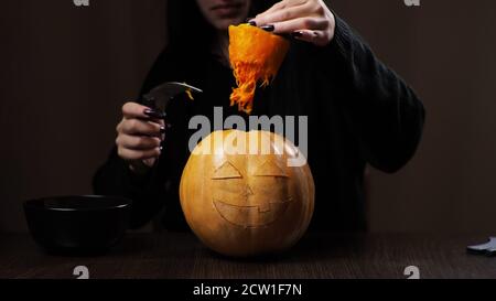 Junge Brünette Frau schnitzt einen Kürbis für Halloween Vorbereitung Stockfoto