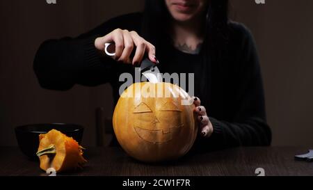 Junge Brünette Frau schnitzt einen Kürbis für Halloween Vorbereitung Stockfoto