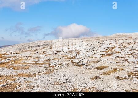 hochplateau mit trockenem Gras und weißen Steinen bedeckt, und ein paar Reisende in der Ferne Stockfoto