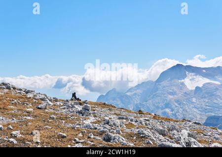 hochplateau, bedeckt mit trockenem Gras und weißen Steinen, mit einem Reisenden, der vor dem Hintergrund der Berge ruht Stockfoto