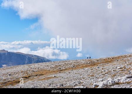 hochplateau mit trockenem Gras und weißen Steinen bedeckt, und ein paar Wanderer in der Ferne Stockfoto