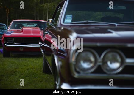 Der amerikanische Oldtimer steht vorne und außer Fokus, und ein weiterer Oldtimer von 1967 oder 1969 steht im Hintergrund im Fokus. Stockfoto