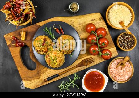 Rotes Risotto mit Tomaten und Chili auf schwarzem Teller. Traditionelle Mahlzeit. Hausmannskost. Würziges Essen. Huhn und Schweinefleisch im Risotto. Stockfoto