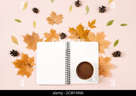 Herbst flach legen mit trockenen Blättern, Notizbuch, Kieferkegel und Kaffeetasse auf pastellbeige Studio-Hintergrund mit Kopieplatz für Werbung. Erntedankfest, Stockfoto