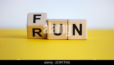 Hand dreht einen Würfel und ändert das Wort Fun to Run. Schöner gelber Tisch, weißer Hintergrund. Lifestyle-Konzept, Kopierraum. Stockfoto
