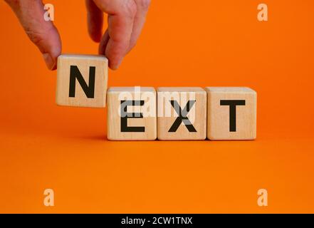 Konzept Wort "next" auf Würfel auf einem schönen orangen Hintergrund. Männliche Hand. Geschäftskonzept. Speicherplatz kopieren. Stockfoto
