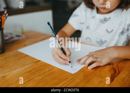 Niedliche fünf Jahre Mädchen tun Mathematik schriftlich Zahlen zu Hause. Bildung und Fernunterricht für Kinder. Homeschooling Konzept Stockfoto