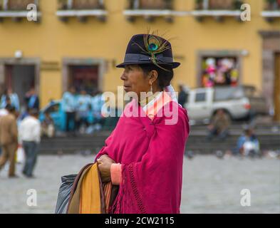 Quito, Ecuador - 2. Dezember 2008: Historische Innenstadt. Nahaufnahme der Frau stehend und bedeckt von rosa Decke hat schwarzen Hut mit einer Pfauenfeder auf ihm Stockfoto