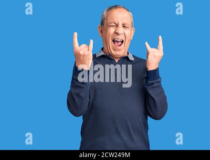 Senior schöner Mann trägt Casual Polo schreien mit verrückten Ausdruck tun Rock-Symbol mit Händen nach oben. Music Star. Heavy Konzept. Stockfoto