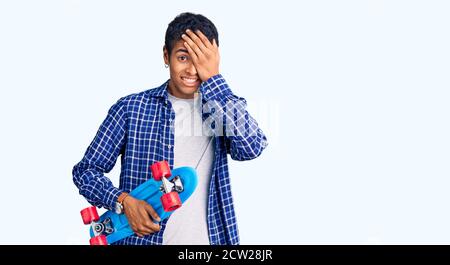 Junger afrikanischer amerikanischer Mann hält Skate gestresst und frustriert mit Hand auf Kopf, überrascht und wütend Gesicht Stockfoto