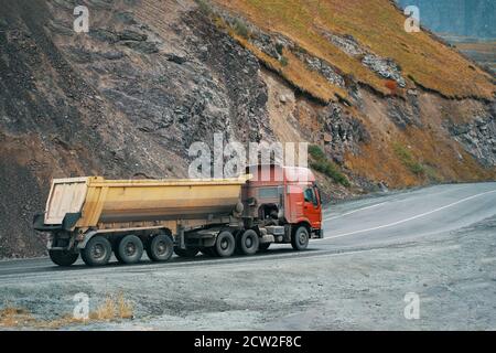 Roter und gelber alter LKW, der Ladung in den Bergen transportiert. Thema Transport Stockfoto