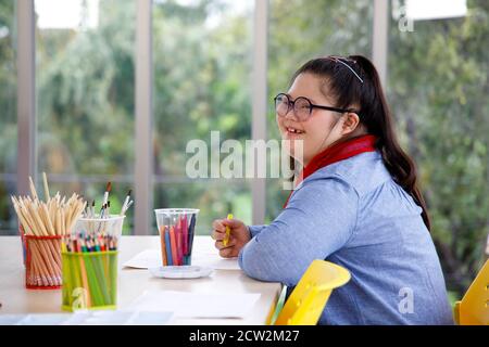 Glücklich asiatische Mädchen mit Down-Syndrom Studium in der Kunstklasse in der Schule. Konzept behindertes Kind lernen in der Schule. Stockfoto