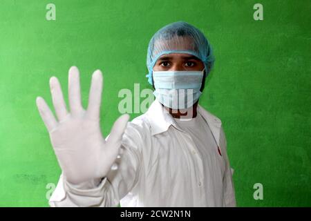Ein junger Arzt in medizinischer Uniform mit einer schützenden Gesichtsmaske und einer Handkleidung mit einem Stoppschild - Stop Corona Virus, covid-19 Konzept. Stockfoto