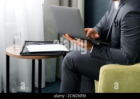 Ein junger Geschäftsmann sitzt im Hotel mit einem Laptop Zimmer Stockfoto