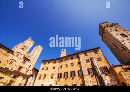 Eine Weitwinkelaufnahme der mittelalterlichen Architektur auf der Piazza della Cisterna von San Gimignano, Italien Stockfoto