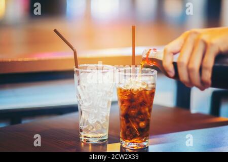 Glas Cola spritzt mit Eis auf Holztisch Hintergrund Stockfoto