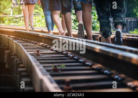 Die Menschen laufen auf der Eisenbahn mit warmem Sonnenlicht auf der Death Railway, Kanchanaburi, Thailand, Traveler on Railroad Stockfoto