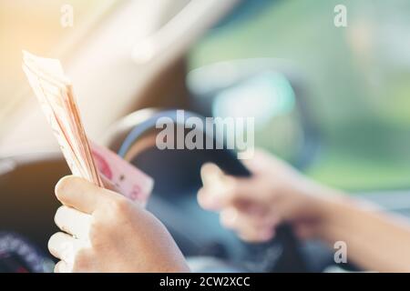 Geldstapel Banknoten oder Scheine in der Hand auf dem Lenkrad des Autos, Konzept der Einnahmen oder Bestechungen, Versicherung oder Kredit, Investitionen Stockfoto
