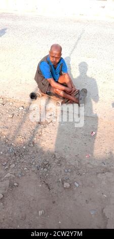 DISTRIKT KATNI, INDIEN - 17. AUGUST 2019: Ein indischer behinderter Mann, der auf der Straße sitzt, um Geld zu betteln. Stockfoto